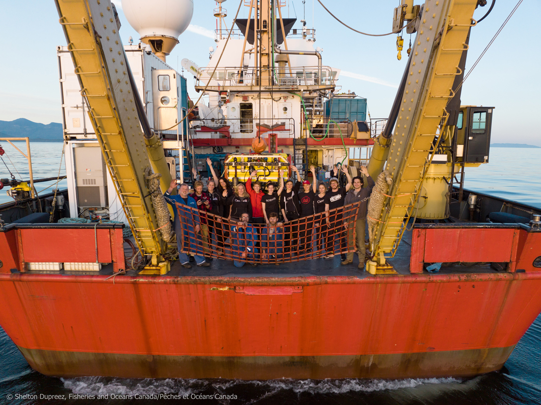 Northeast Pacific Deep-Sea Diversity Expedition crew aboard the Canadian Coast Guard Ship J.P. Tully standing at the stern and waving.