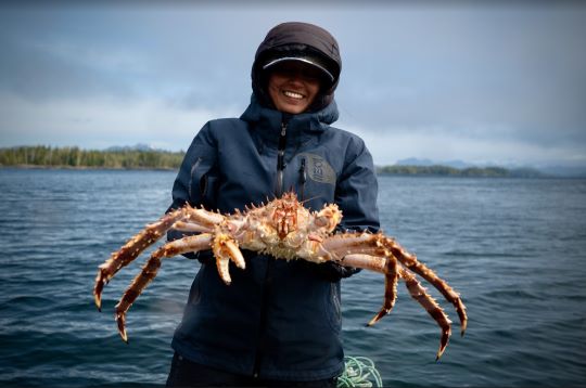 femme en le réseau des professionnels de l’océan en début de carrière, en tenue de plongée, tenant un crabe.