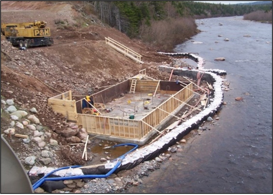 Construction d'un bâtiment à côté d'un ruisseau montrant l'utilisation d'un batardeau.