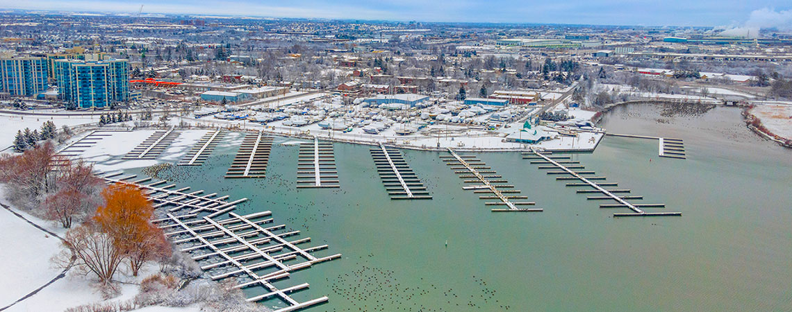 Aerial view of the Whitby Ontario small craft harbour during the winter months.  There are no boats, only empty boat slips and open water.  The town of Whitby is seen in the background.