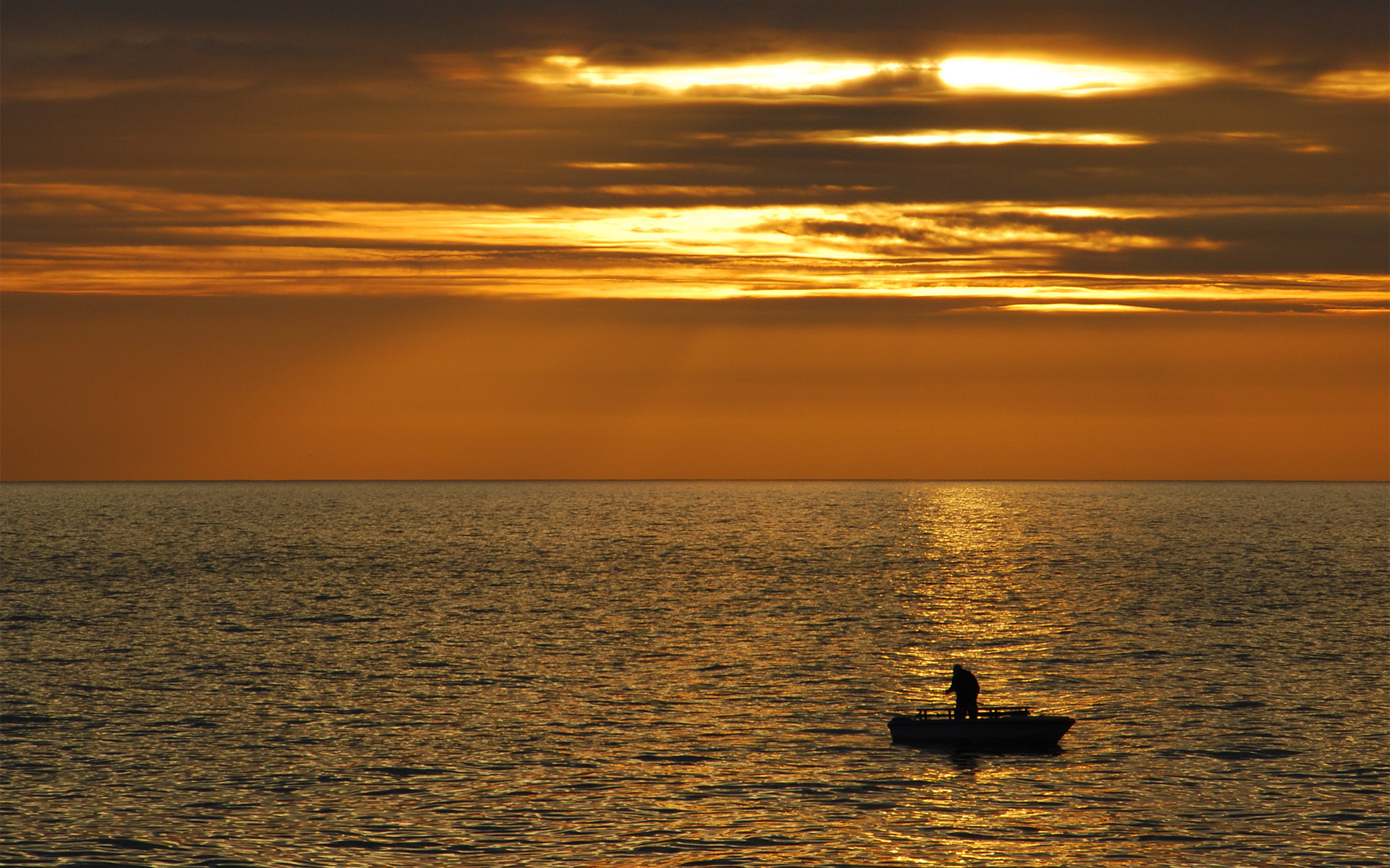 Une personne dans un petit bateau de pêche au coucher du soleil