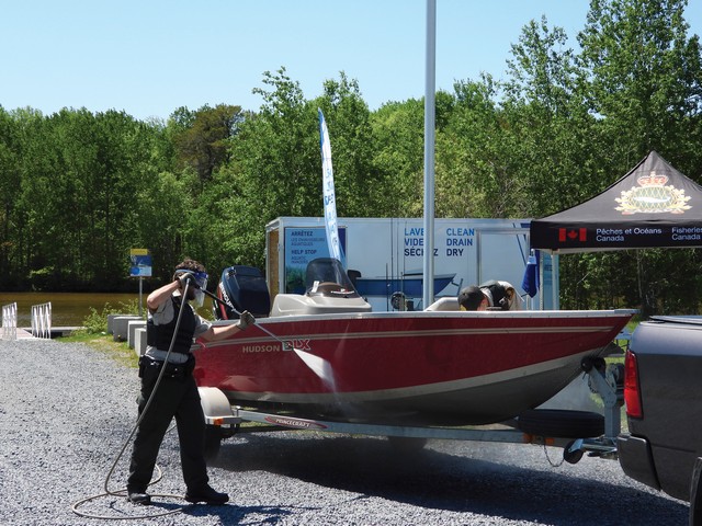 Agent des pêches du Ministère de Pêches et Océans Canada (MPO) qui lave une embarcation de plaisance avec de l’eau chaude à haute pression à la suite de sa sortie de l’eau